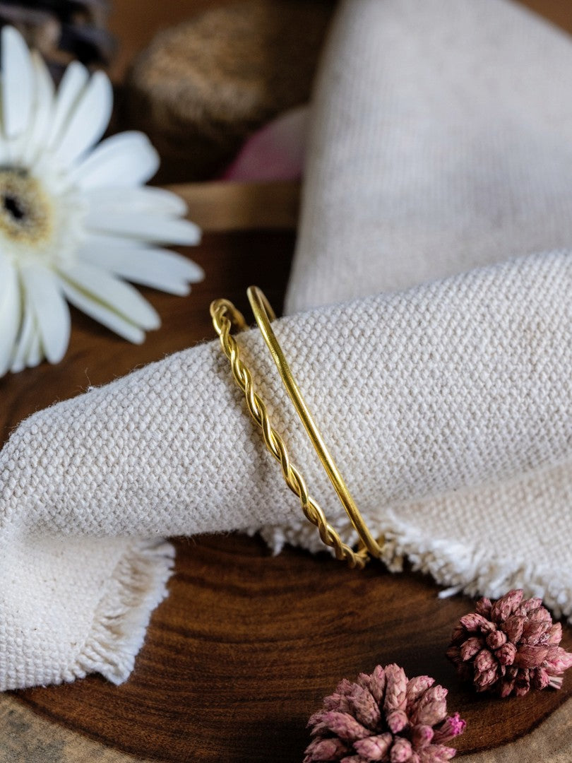 Gold bangle on a white napkin with flowers in the background