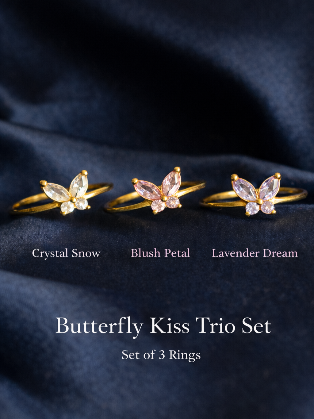 Butterfly-shaped rings labeled 'Crystal Snow', 'Blush Petal', and 'Lavender Dream' on a dark fabric background.
